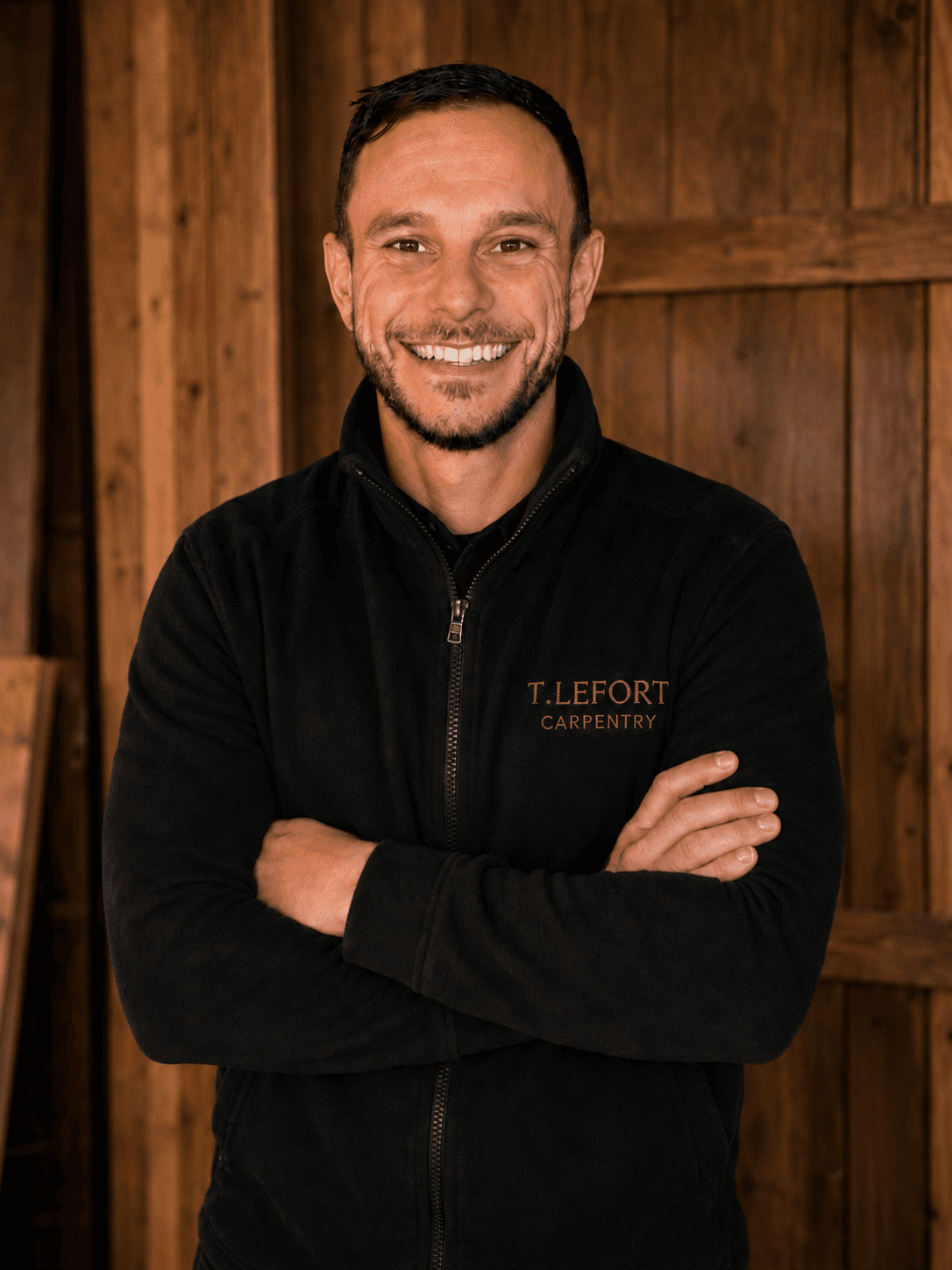 Thomas Lefort, founder of T Lefort Carpentry, standing in front of a timber workshop backdrop
